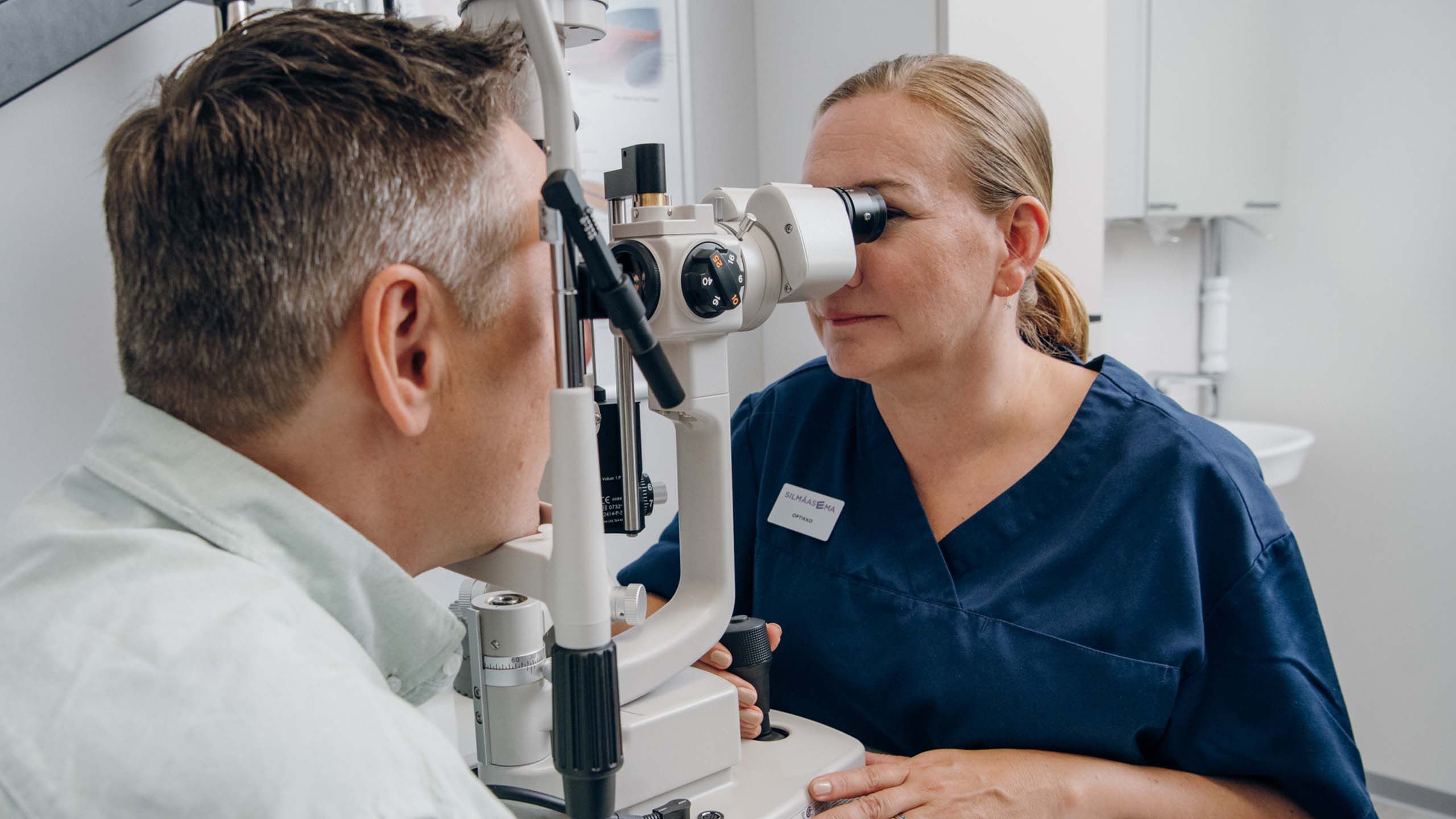 Sairaala-optikko tutkii asiakaan silmi&auml; mikroskoopilla.